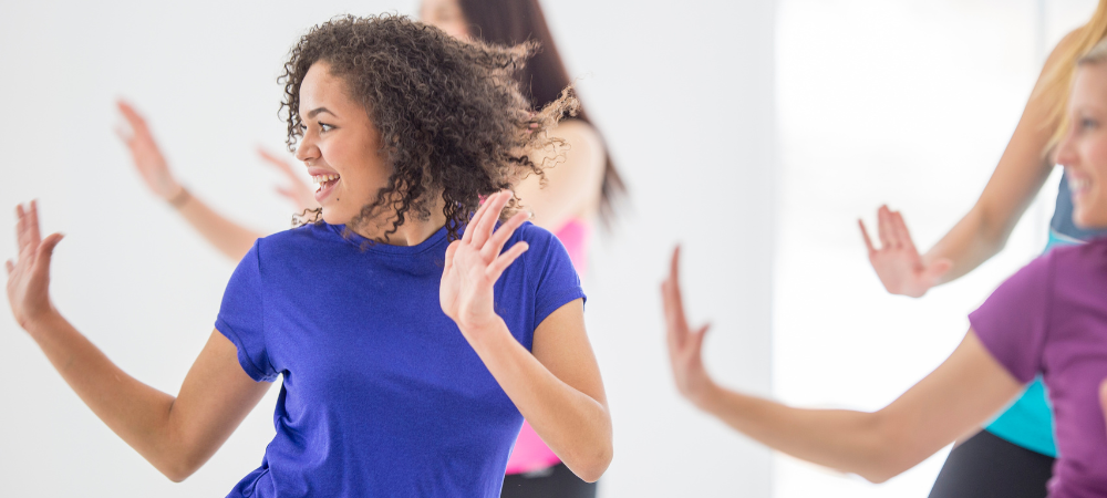 female in blue shirt with hands up exercising